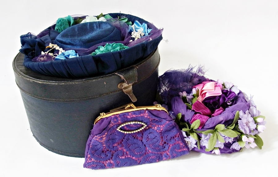 Two vintage style hats heavily decorated with faux-flowers, ribbons, etc. and a evening handbag with