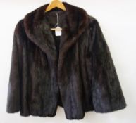 A dark mink jacket with bell sleeves, initials embroidered in the lining