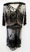 A 1920's black net dress, heavily beaded, the sleeves also with beaded decorations