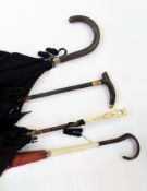 Four umbrellas, one with a carved bone handle, the other with a simulated bamboo handle and two