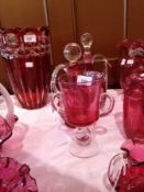Two cranberry and clear wine ewers with spherical stoppers and a cranberry and clear two-handled