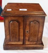 A Victorian walnut miniature cabinet, the pair of panel doors opening to reveal three small