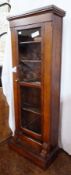 Stained wood bookcase having four narrow shelves enclosed by glazed panel door on plinth base