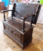 Reproduction carved oak monk's bench the hinged top with foliate scroll carving to the top, shield