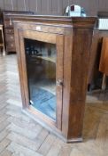 Oak wall-hanging corner cabinet having two curved shelves enclosed by framed glazed panel door, 82cm