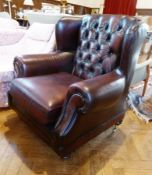Modern leather wing armchair with button back upholstered in dark burgandy coloured hide on turned