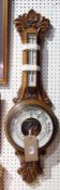 Victorian aneroid wheel barometer with enamelled temperature and pressure dials within a carved