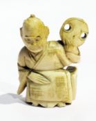 An old Japanese carved ivory netsuke of an old man with a fan on his shoulder