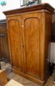 Mid Victorian mahogany compactum, the arched panelled doors enclosing hanging space and trays and
