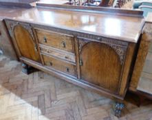 A reproduction oak sideboard, with three central drawers flanked by foliate carved arched cupboards,