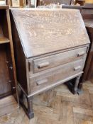 An oak reproduction bureau, the fall front enclosing cupboards with two long drawers below, on