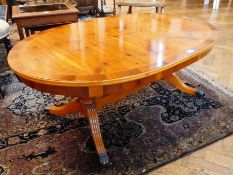 A modern mahogany oval coffee table, with column support on splade and reeded legs with lion paw