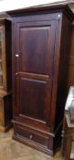 A stained pine cupboard with straight moulded cornice, the fielded panel door enclosing hanging