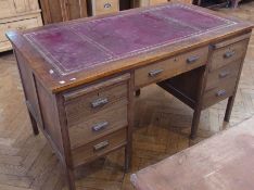 20th Century oak knee hole desk with leather insert top, an arrangement of seven drawers around