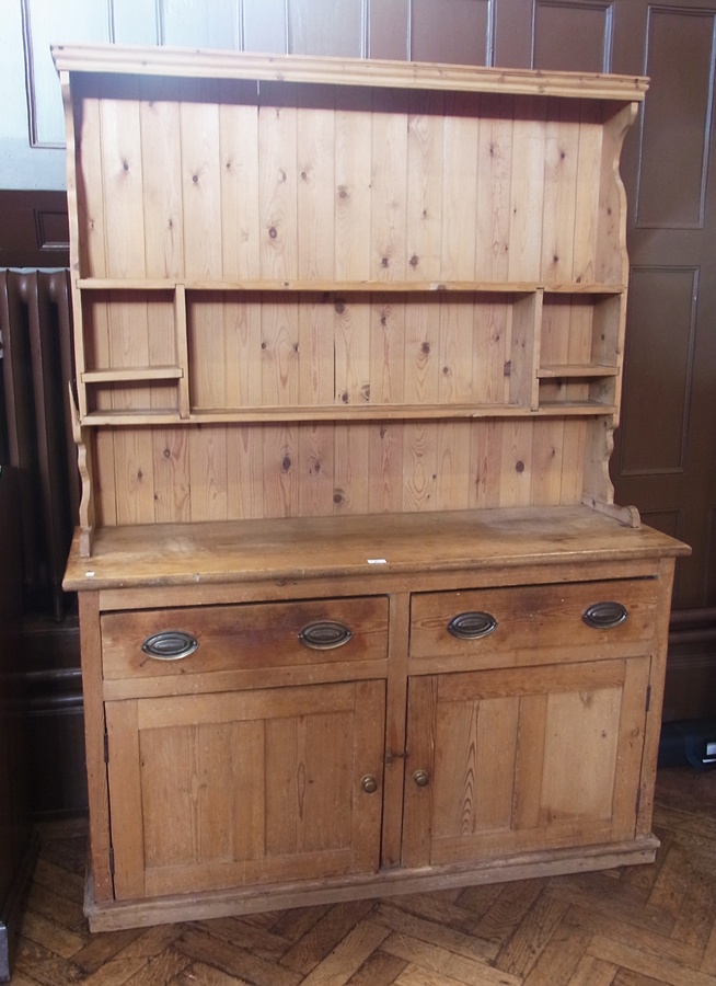 A pine dresser with shelves and cupboards above, pair of drawers with cupboards below, with brass