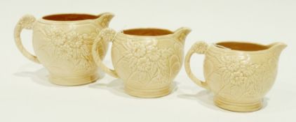 Three Arthur Wood pottery graduated jugs, floral moulded with peach coloured glaze