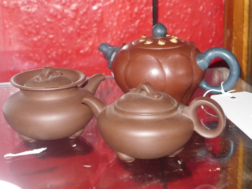 A Chinese terracotta teapot marked `Water lily` made by Seung Sin Wong together with another two
