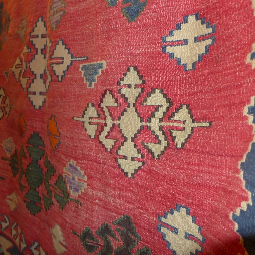 A Persian Kilim carpet the red field decorated with repeating geometric patterns in blue border