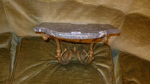 An early C20th French gilt metal wall bracket of serpentine outline with inset grey marble top