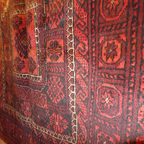 A fine North East Persian Turkoman rug repeating panel motifs on a terracotta field guarded by