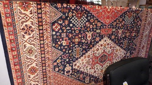 A Caucasion style carpet the navy blue field decorated with central medallion and repeating motifs