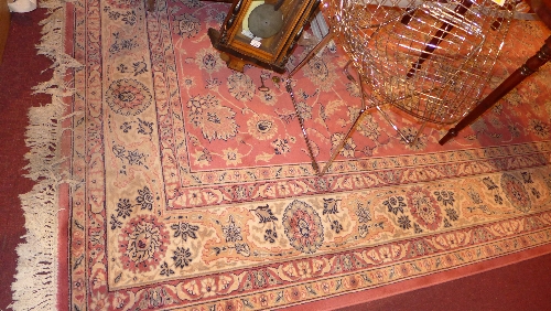 A Persian style carpet of large size the cream field decorated with repeating  flower head motifs