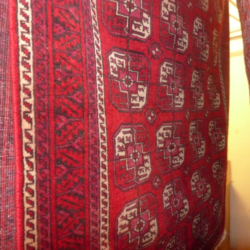 A fine North East Persian Turkoman rug having repeating Goul motifs on a rouge field within