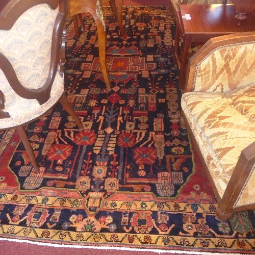 A Persian Baktir carpet having a central medallion on a navy blue field surrounded by borders L 287