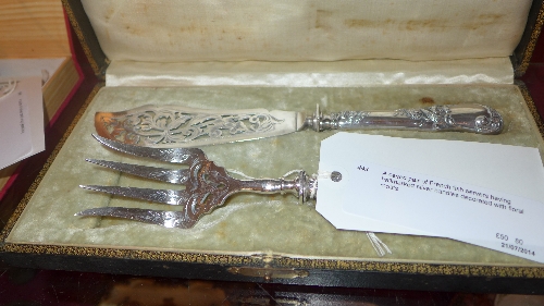 A cased pair of French fish servers having hallmarked silver handles decorated with floral motifs