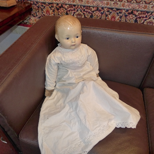 An Effanbee doll with papier mache head and in linen dress