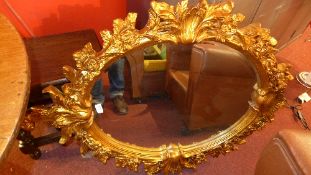 A French style oval form mirror in ornate gilt frame