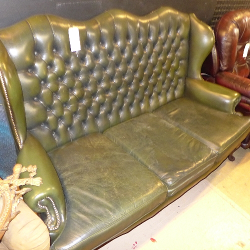 A C20th mahogany three seater winged back sofa upholstered in green button leather on cabriole