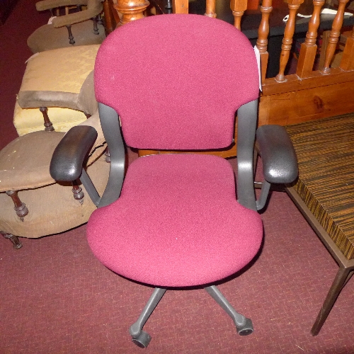 A Herman Miller desk chair upholstered in maroon fabric on adjustable swivel supports