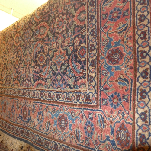 An early C20th Persian carpet having floral motifs on a midnight blue field surrounded by one