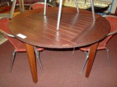 A circular teak garden table of slatted form raised on square section supports