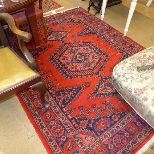 A hand knotted Persian rug the rouge ground with central medallion and flowerhead border W 165 L