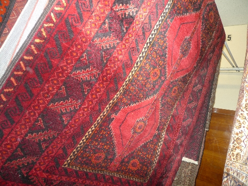 A fine North East Persian Turkoman rug  bearing a repeating pole medallion on a rouge field within