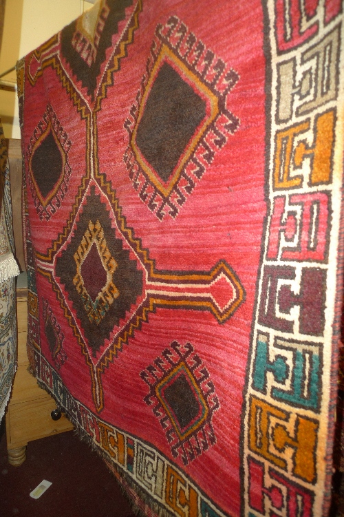 A hand knotted Persian Qashgai rug the red field with central medallion within a geometric border