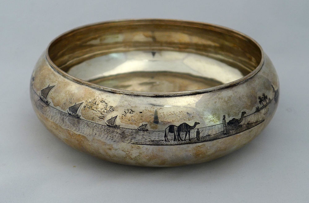 A large Iraqi niello silver bowl decorated with palm trees on river scene with a boat in the