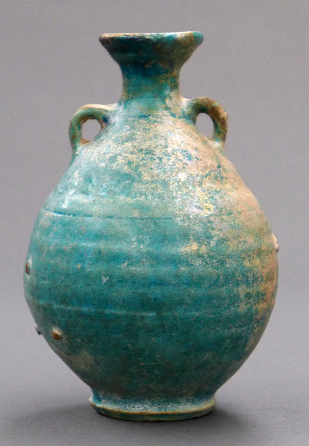 A Sasanid twin handled turquoise glazed ewer of bulbous form with flared neck on stepped base H 18.5