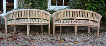 A pair of teak garden benches, of recent manufacture, each with arched backrest with vertical