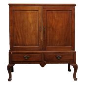 A George II mahogany linen press with a moulded cornice and twin panelled doors enclosing shelves,