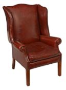 A leather upholstered wing armchair in George II style, late 20th century, the shaped back above
