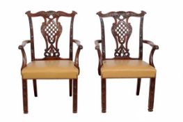 A pair of George III style mahogany elbow chairs, 19th century, with heavily carved and pierced