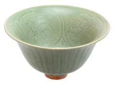 An Asian celadon bowl, heavily potted, rising on a straight foot, with flaring rim, moulded, to the