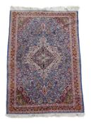 A Kashan rug, the central navy and ivory medallion within a profusely foliate decorated field,