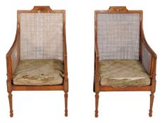 A pair of Sheraton Revival satinwood and painted bergere library chairs, late 19th early 20th