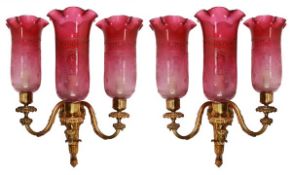 A pair of gilt bronze and cranberry glass fitted three light wall appliques, early 20th century,