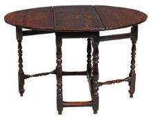 A Queen Anne oak gateleg circa 1710 with an oval folding top on baluster turned legs joined by