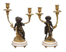 A pair of French patinated and gilt bronze twin light figural candelabra, circa 1880, the fluted